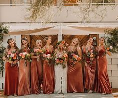 a group of women standing next to each other in front of a white building holding bouquets