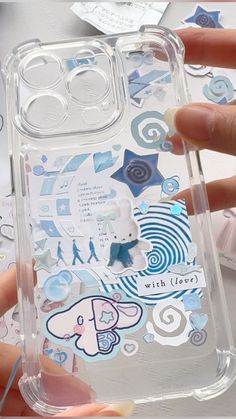 a person holding a clear case with stickers on it and some other things in the background