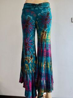 "Handmade Materials: Cotton, Lycra Description These tie dye splatter bell bottoms are made for movement! Perfect for yoga and flow activities. Handmade and hand-dyed, available from a variety of 4 colour ways to choose from 🌸 The fitting around the thigh is flattering & shaping until the material billows out at the knee into a wide flare. Featuring drawstrings on either side of the thigh that can be cinched for shape and length adjustment! The material consists of a quality Rayon 95% spandex 5 Fitted Hippie Flare Pants, Hippie Fitted Flare Pants, Multicolor Flare Cotton Bottoms, Multicolor Cotton Flare Bottoms, Multicolor Stretch Flare Pants, Hippie Flare Stretch Pants, Hippie High-waisted Fitted Pants, Fitted Hippie Flares For Summer, Cotton Flare Pants For Festivals