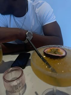 a man sitting at a table with a plate of food and drinks in front of him