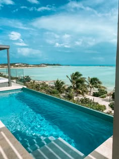 an empty swimming pool in front of the ocean with palm trees and blue skies above