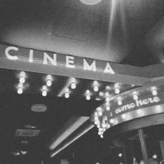 a black and white photo of the entrance to a movie theater with lights on it