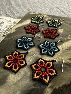 six beaded earrings sitting on top of a rock