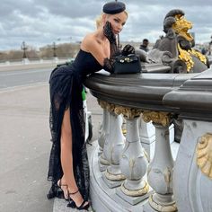 a woman is leaning on a fence with her hand on the ground and looking at something