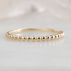 The Gold Beaded Stacking Ring in 14K Yellow Gold on White Marble Plain Gold Wedding Bands, Beaded Stacking Rings, Simple Wedding Band, Watermelon Tourmaline Ring, Birthstone Stacking Rings, Simple Wedding Bands, Custom Wedding Band, Black Diamond Engagement, Black Diamond Ring Engagement