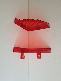 two red shelfs on the wall, one with an umbrella shaped shelf above it