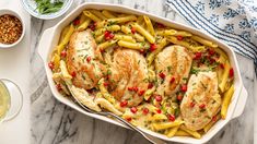 a casserole dish filled with chicken, pasta and vegetables on a marble table