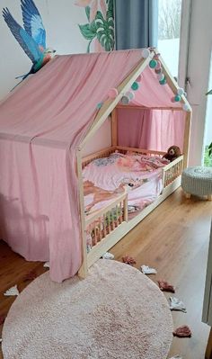 a child's bed with a pink canopy over it and birds on the wall