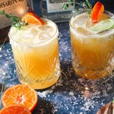 two glasses filled with orange margaritas on top of a table