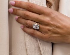 a woman's hand with a diamond ring on her finger, wearing a white coat