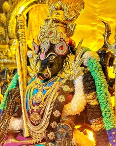 an elaborately decorated statue is displayed in front of a gold background