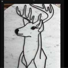 a metal deer with antlers on it's head sitting on a marble table