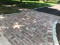 a brick sidewalk with grass and trees in the background