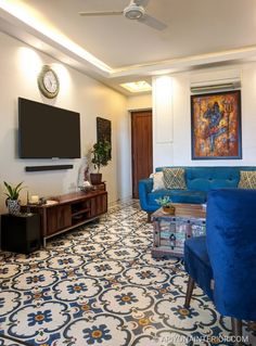 a living room filled with blue couches and a flat screen tv mounted to the wall