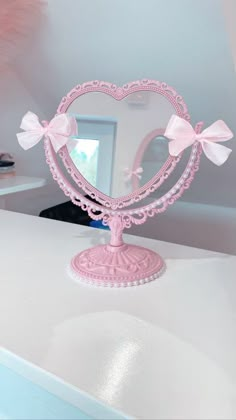 a pink heart shaped mirror sitting on top of a white counter next to a window