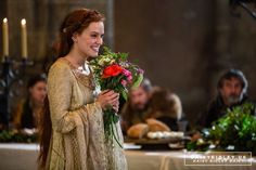 a woman dressed in medieval clothing holding flowers