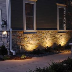 some lights that are on the side of a house in front of a stone wall