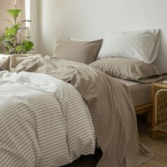 an unmade bed in a bedroom next to a window with plants on the windowsill