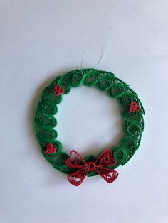 a christmas wreath made out of green paper with red bows and buttons on the front