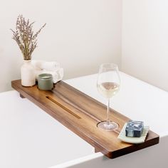 a glass of wine on a wooden tray next to a candle and soap cubes