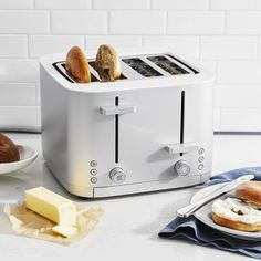 a toaster sitting on top of a counter next to plates with bread and butter