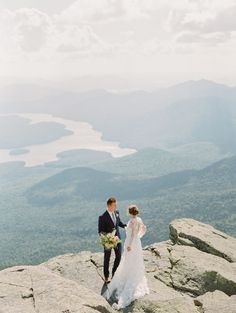 a bride and groom standing on top of a mountain