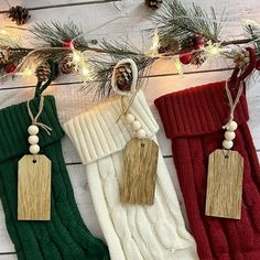 three christmas stockings hanging from a tree with pine cones and lights on the branches behind them