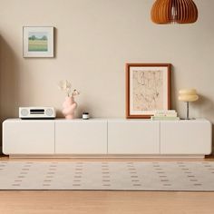 a living room with a large white entertainment center and pictures on the wall above it