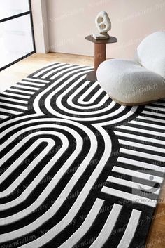 a black and white area rug with an abstract design on the floor in front of a window