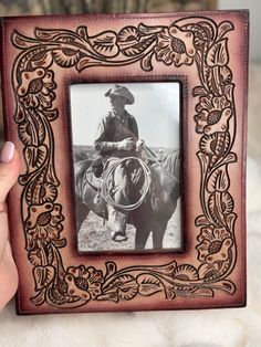 a person holding up a wooden frame with an image of a cowboy on it