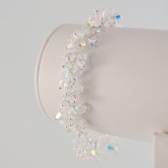 This wedding bracelet has serious sparkle. It is made with over 75 genuine Swarovski crystals, linked together to form a long cluster. The crystals are clear, with an aurora borealis, or AB, coating. This coating reflects the colours all around the crystals - a very pretty effect. It reminds me of the sun glinting off the snow and frost on a winter morning. I have used sterling silver components throughout, including a petite lobster clasp to secure the bracelet. This bracelet has a bit of weigh Sparkling Crystal Bracelet For Anniversary, White Sparkling Crystal Bracelets, White Sparkling Cubic Zirconia Crystal Bracelet, Sparkling White Cubic Zirconia Crystal Bracelet, White Crystal Bracelets With Sparkling Stones, White Crystal Bracelet With Sparkling Stones, Silver Crystal Bracelet With Faceted Beads For Wedding, Crystal Faceted Bracelets For Weddings, Crystal Jubilee Bracelet For Anniversary