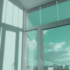 an open window with the view of buildings and clouds in the sky from inside it