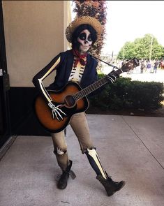 a skeleton playing a guitar on the sidewalk