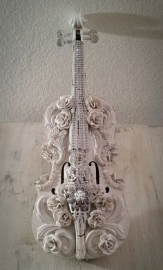 a white violin sculpture sitting on top of a wooden table