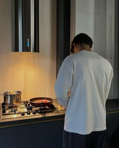 a man standing in front of a stove top with a pan on it's burner