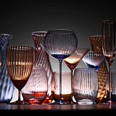 many different colored wine glasses lined up on a table