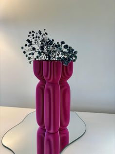 a purple vase with flowers in it on a white table next to a lamp shade