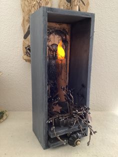 a candle is lit in an old wooden box with branches and twigs on the bottom