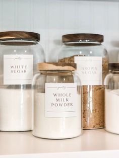 three jars with labels on them sitting on a counter top next to other containers that are labeled whole milk powdered and brown sugar