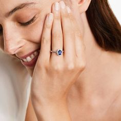 a woman holding her hand to her face with a ring on it's finger