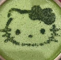 a bowl filled with green liquid that has a hello kitty drawn on it