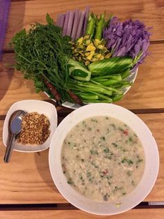 a bowl of soup next to two bowls of vegetables and rice on a wooden table