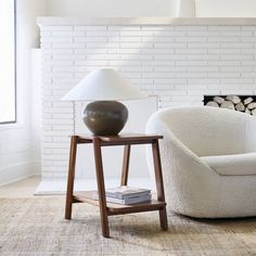 a white chair sitting next to a lamp on top of a table in a living room