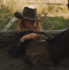 a woman laying on the ground wearing a cowboy hat