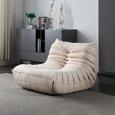 a living room with a large white bean bag chair in front of a book shelf