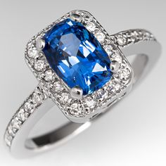 This gorgeous no heat blue sapphire ring is centered with a 1.64 carat cushion cut sapphire set into a four-prong head and is bordered with eighteen (18), bead set, round brilliant cut diamonds. The top face of the shank is accented with a row of seven (7), bead set, round brilliant cut diamonds on each side. The ring measures 10.2mm at the top, rises 6.4mm above the finger, tapering to 1.7mm wide and 1.1mm thick at the base of the shank. The ring is currently a size 4.75 and we offer compliment Fine Jewelry Blue Radiant Cut Sapphire Ring, Classic Blue Radiant Cut Sapphire Ring, Blue Sapphire Ring With Radiant Cut And Accent Stones, Blue Square Cut Sapphire Ring Fine Jewelry, Fine Jewelry Blue Sapphire Ring Square Cut, Elegant Blue Sapphire Ring With Radiant Cut, Elegant Blue Radiant Cut Sapphire Ring, Blue Square Cut Sapphire Ring, Blue Square Cut Jewelry With Halo Setting