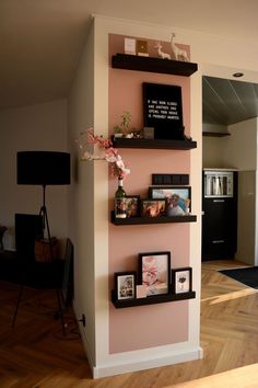 three shelves with pictures and flowers on them in the corner of a living room area