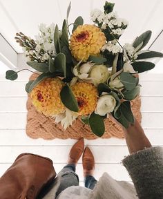 two people holding flowers in their hands while standing on the floor next to each other