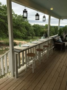 an outdoor dining area with wooden floors and white railings on the side of a house