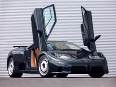 a black sports car parked in front of a garage door with its open doors opened